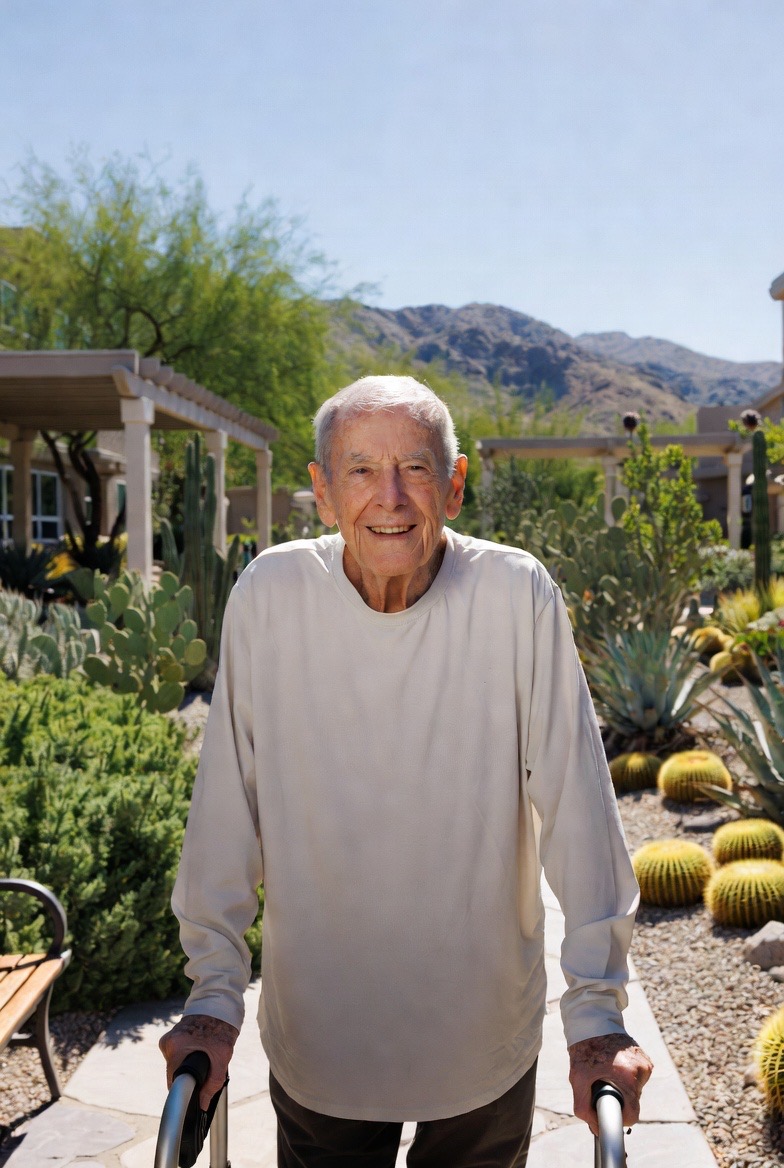 Elderly man with a walker in a landscaped courtyard with mountain views