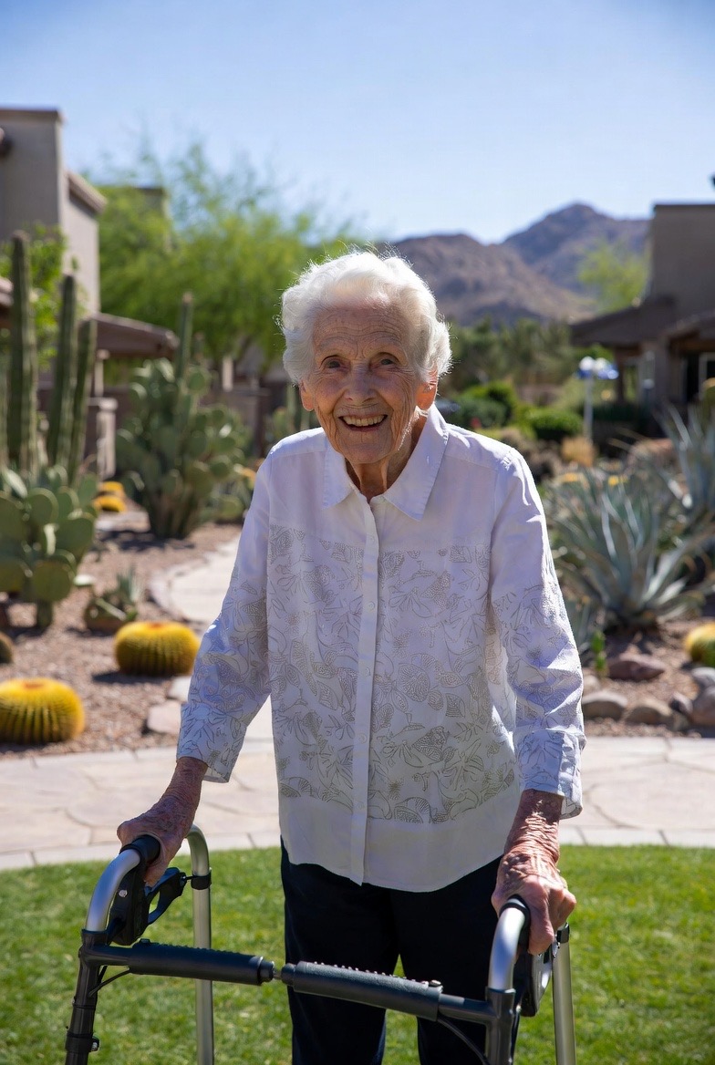 Elderly woman smiling in a desert garden with mountains in the background