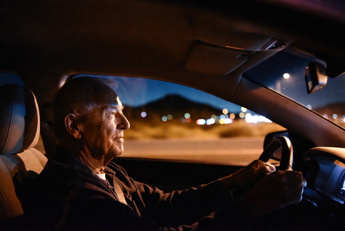 Clear nighttime view of city lights and mountains through a car windshield