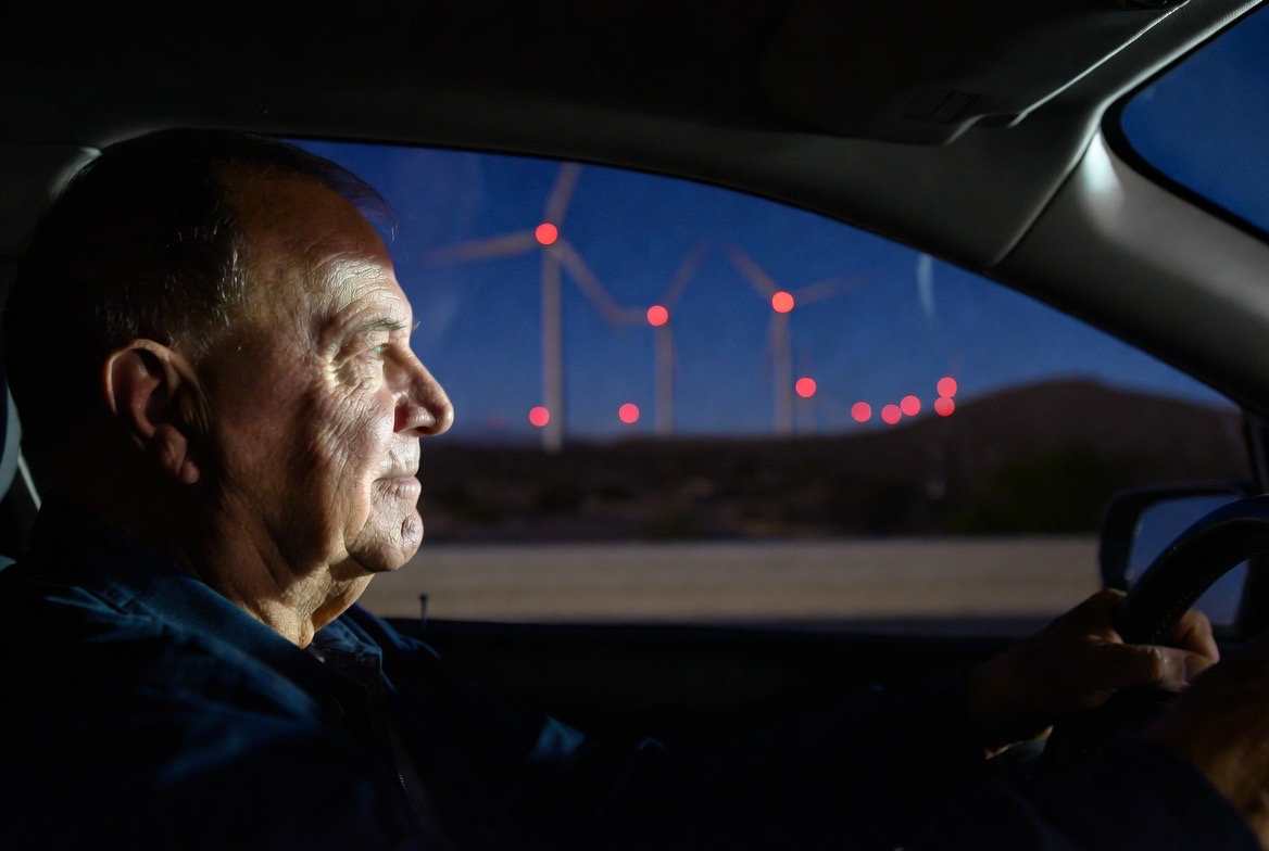 Senior man driving at night past wind turbines in the Coachella Valley, the familiar San Gorgonio Pass landmark for Calimesa residents