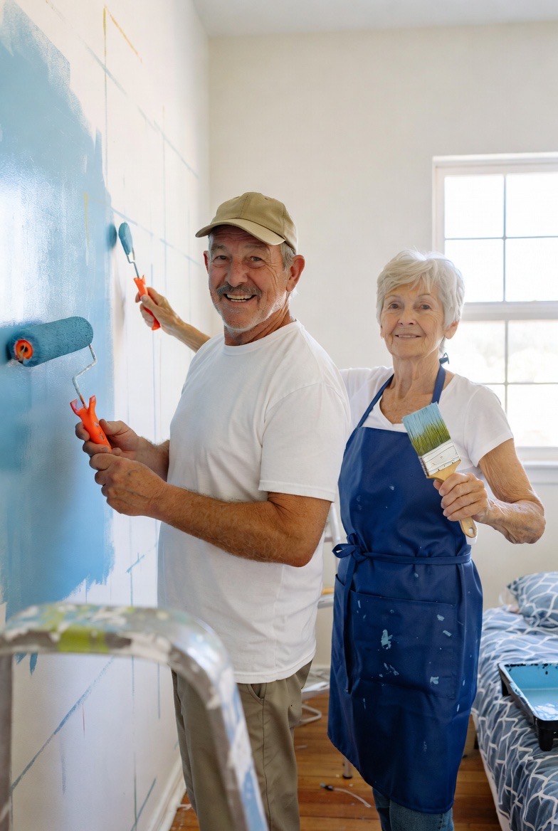 Happy senior couple painting their home together, enjoying an active retirement