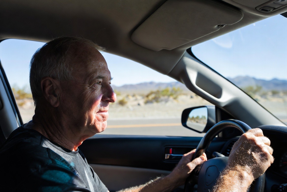 Senior man driving in the desert, where halos and glare from dysphotopsia can affect night driving